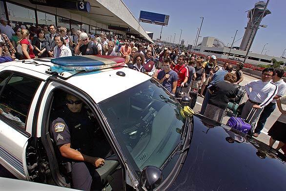 Airline passengers wait outside Terminal 3 at Los Angeles International Airport on Wednesday afternoon. Authorities say a man walked up to officers on the upper-level roadway and said he was a terrorist and had a bomb.