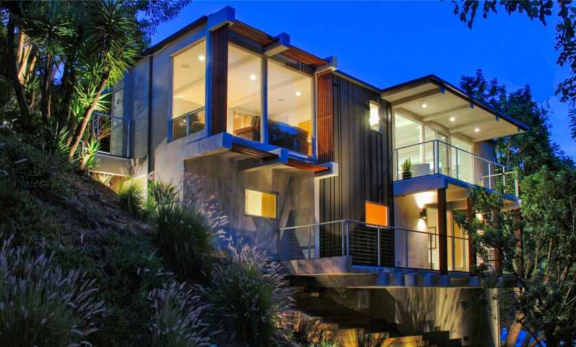 The secluded two-story home takes in canyon views from a balcony with a sauna and from an outdoor lounge with a waterfall.