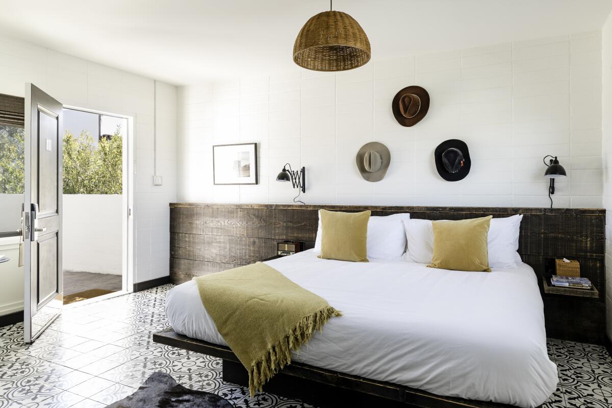 A guest room with cowboy hats on the wall and a basket ceiling light