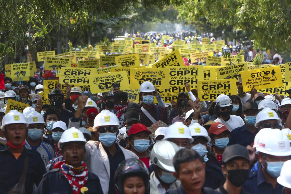 Manifestantes contrarios al golpe de Estado, con cascos de construcción y mascarilla,