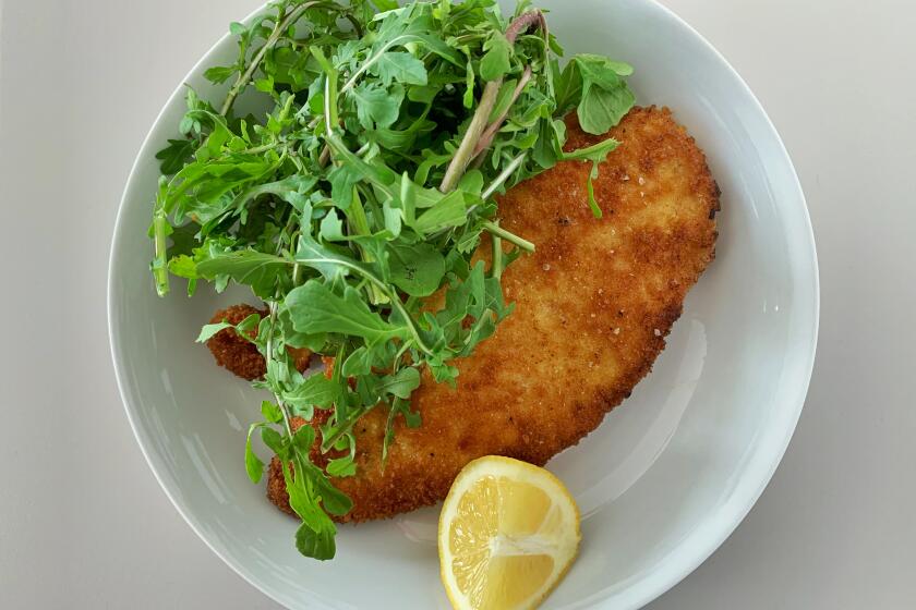Classic chicken piccata, breaded and shallow fried, is served with arugula and lemon.