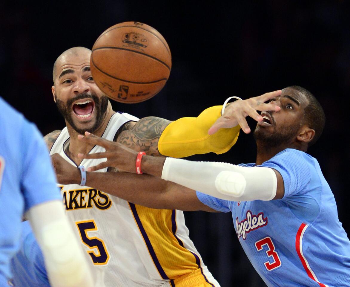 Lakers forward Carlos Boozer (5) and Clippers point guard Chris Paul (3) get tangled battling for a loose ball in the second half Sunday night at Staples Center.