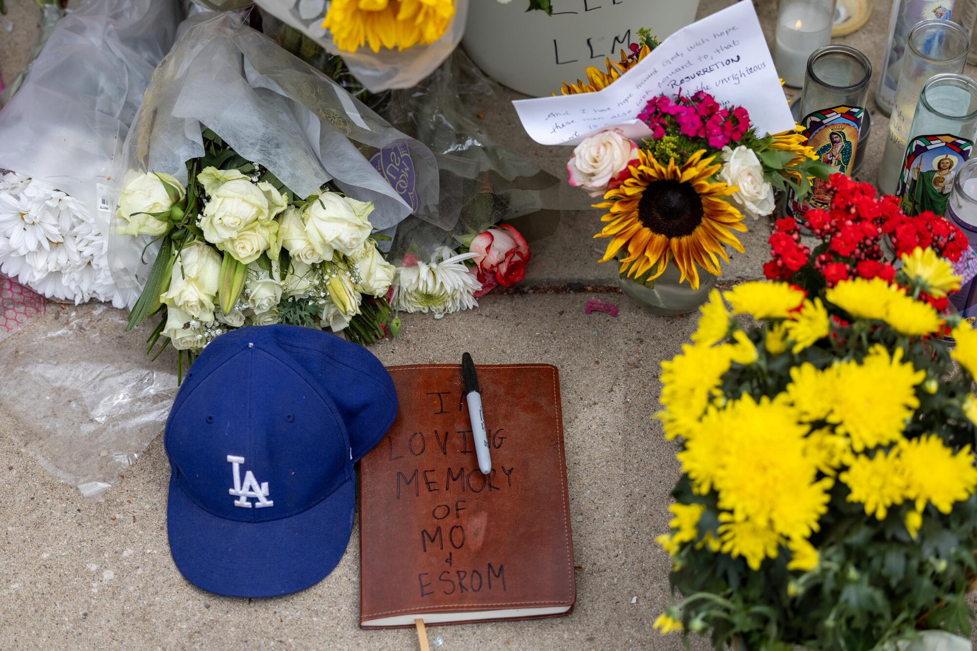 A sidewalk memorial featuring flowers, notes and a Dodgers hat