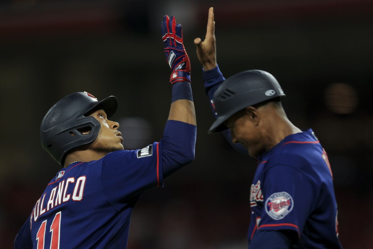 Minnesota Twins' Jorge Polanco, left, high-fives Tony Diaz, right, after hitting a three-run home run during the ninth inning of a baseball game against the Cincinnati Reds in Cincinnati, Tuesday, Aug. 3, 2021. (AP Photo/Aaron Doster)
