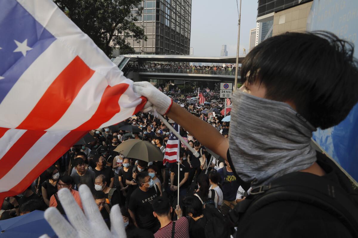 A protester waves a U.S. flag in Hong Kong, Sunday, Sept. 8, 2019. Thousands of demonstrators in Hong Kong urge President Donald Trump to “liberate” the semi-autonomous Chinese territory during a peaceful march to the U.S. consulate, but violence broke out later in the business and retail district after protesters vandalized subway stations, set fires and blocked traffic. (AP Photo/Kin Cheung)