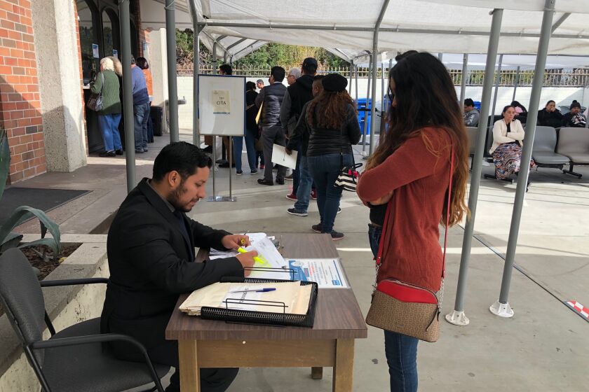 Un funcionario diplomático revisa los documentos de una usuaria en la entrada del consulado en LA.