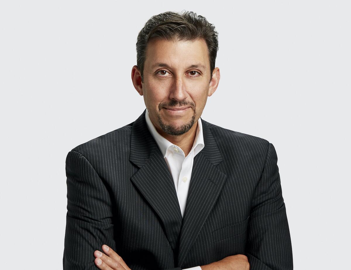 A headshot of Scott Altman in a pin-stripe suit and goatee, with arms crossed.