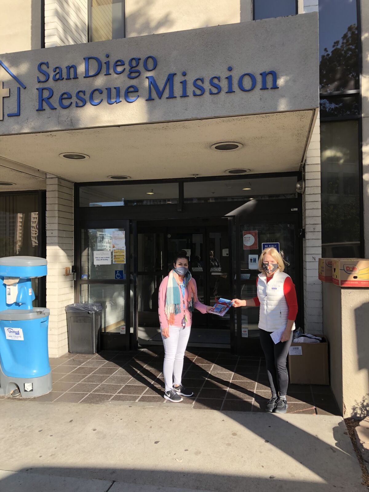 Barbara Burton Graf (right) donates copies of her book to the San Diego Rescue Mission.