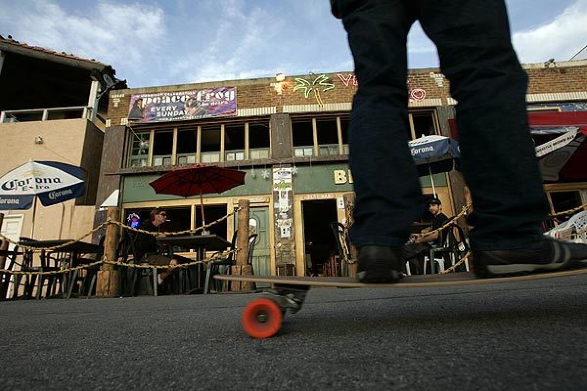 A skateboarder passes diners along Ocean Front Walk near the former Venice West Cafe, L.A.'s headquarters for artists, poets, musicians and other Beat adherents in the 1960s. The city may designate the site a historic-cultural landmark.