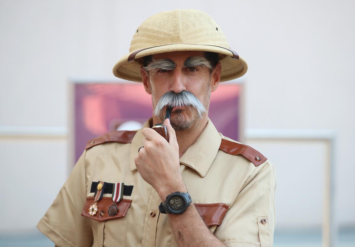 Steve Campenos dressed as Col. Mustard, pretends to smoke a toy pipe during the Clue Character Costume Contest.