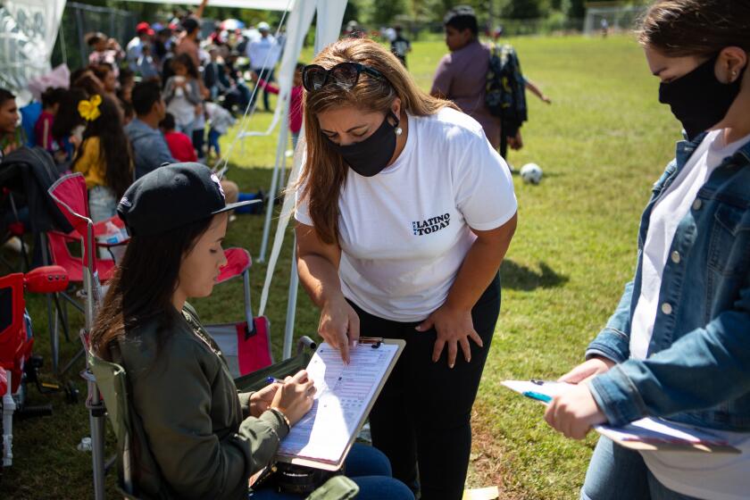 RALEIGH, NC - SEPTEMBER 20: Sandra Amado Gomez and her daughter Aylen Agostina Gomez registers a woman to vote during halftime at the championship game of soccer on Sunday, Sept. 20, 2020 in Raleigh, NC. North Carolina is gearing up to be a swing state in the 2020 election and Latino voters will play a big part in the outcome. (Jason Armond / Los Angeles Times)