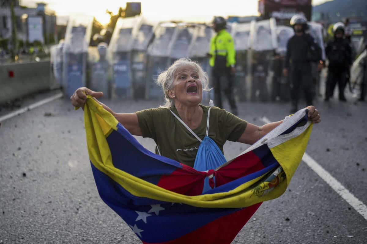 Consuelo Márquez sostiene una bandera venezolana frente a la policía que bloquea 