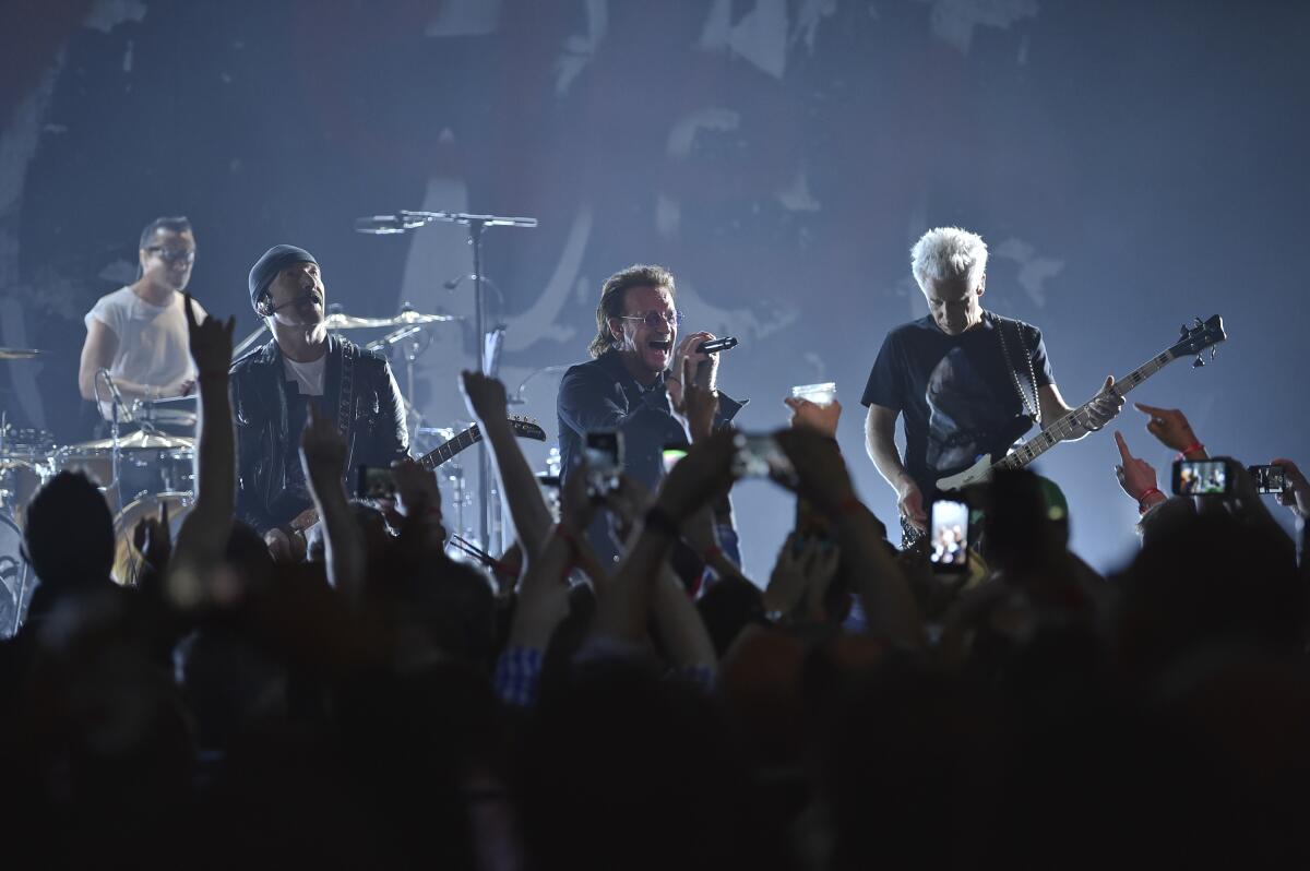 Larry Mullen Jr., the Edge, Bono and Adam Clayton of U2 perform in front of an audience.