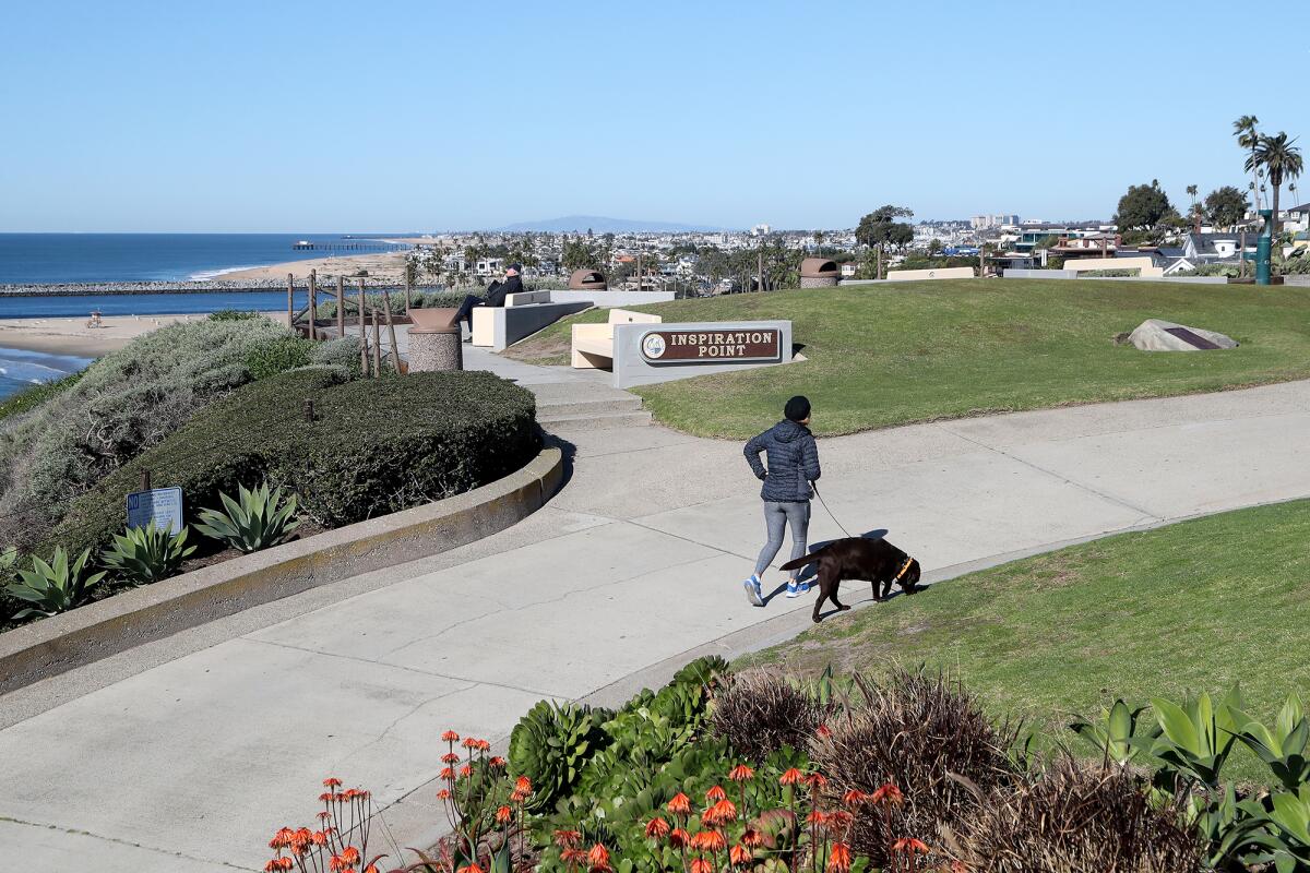 A woman walks her dog by Inspiration Point in Newport Beach.