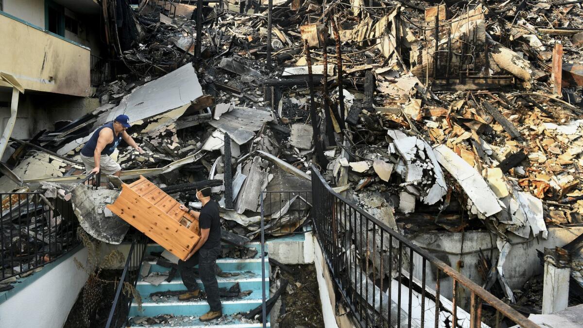 Jeff Rodriquez, left, and his son Casey help a friend move belongings after the Thomas fire destroyed most of an apartment building on North Kalorama Street in Ventura.