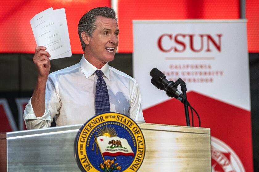 NORTHRIDGE, CA - OCTOBER 06, 2021: Gov. Gavin Newsom holds up some of the 7 bills he signed that are part of a $47.1 billion higher education package, the highest level of funding in state history. Newsom made the announcement during a press conference at Cal State University, Northridge. (Mel Melcon / Los Angeles Times)