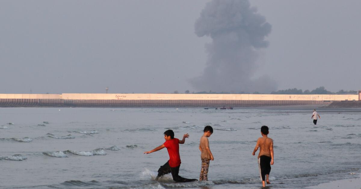 Photo: latimes.com Three boys play in the shallow waters of the Strait of Hormuz, as a plume of smoke rises from an explosion in the