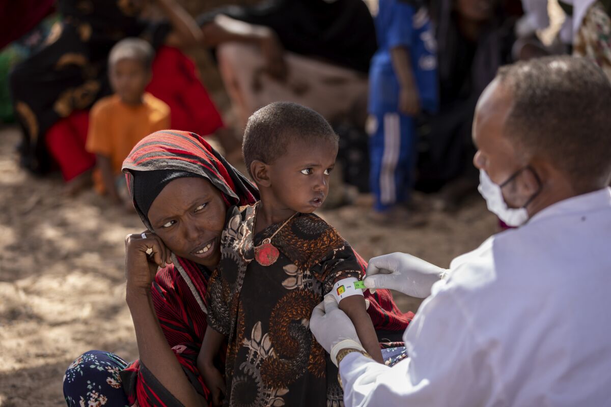 A nurse measures the arm of Nimo Abdi, who is suffering from diarrhea and vomiting and is receiving treatment for malnutrition, as she is held by her mother Shamis Dhire, at a UNICEF-supported mobile clinic at Barare village in the Higloley Woreda of the Somali region of Ethiopia Thursday, Jan. 20, 2022. In Ethiopia's Somali region, people have seen the failures of what should have been three straight rainy seasons and Somalia, Kenya, and now Ethiopia have raised the alarm about the latest climate shock to a fragile region. (Mulugeta Ayene/UNICEF via AP)