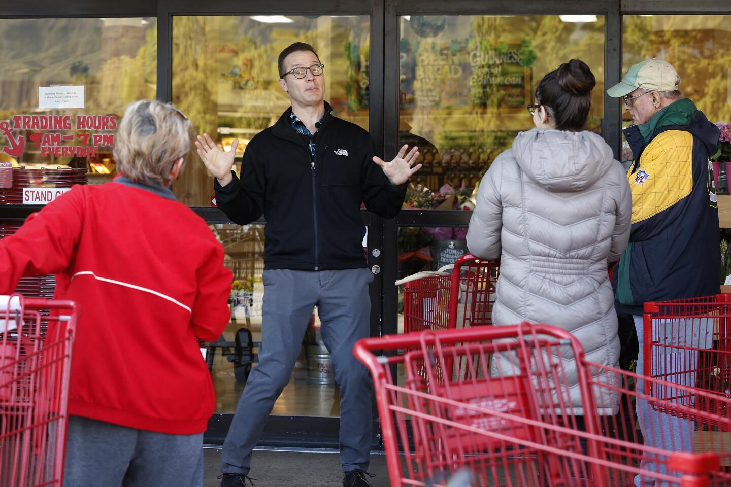 An employee of the Trader Joe's store in Monrovia tells customers waiting in line that it would open doors to everyone at 9 a.m., not just seniors, who arrived believing doors would open earlier to older residents, as some of the people were told by employees and it was reported. Some grocery outlets were offering special morning hours of shopping to accommodate older residents.