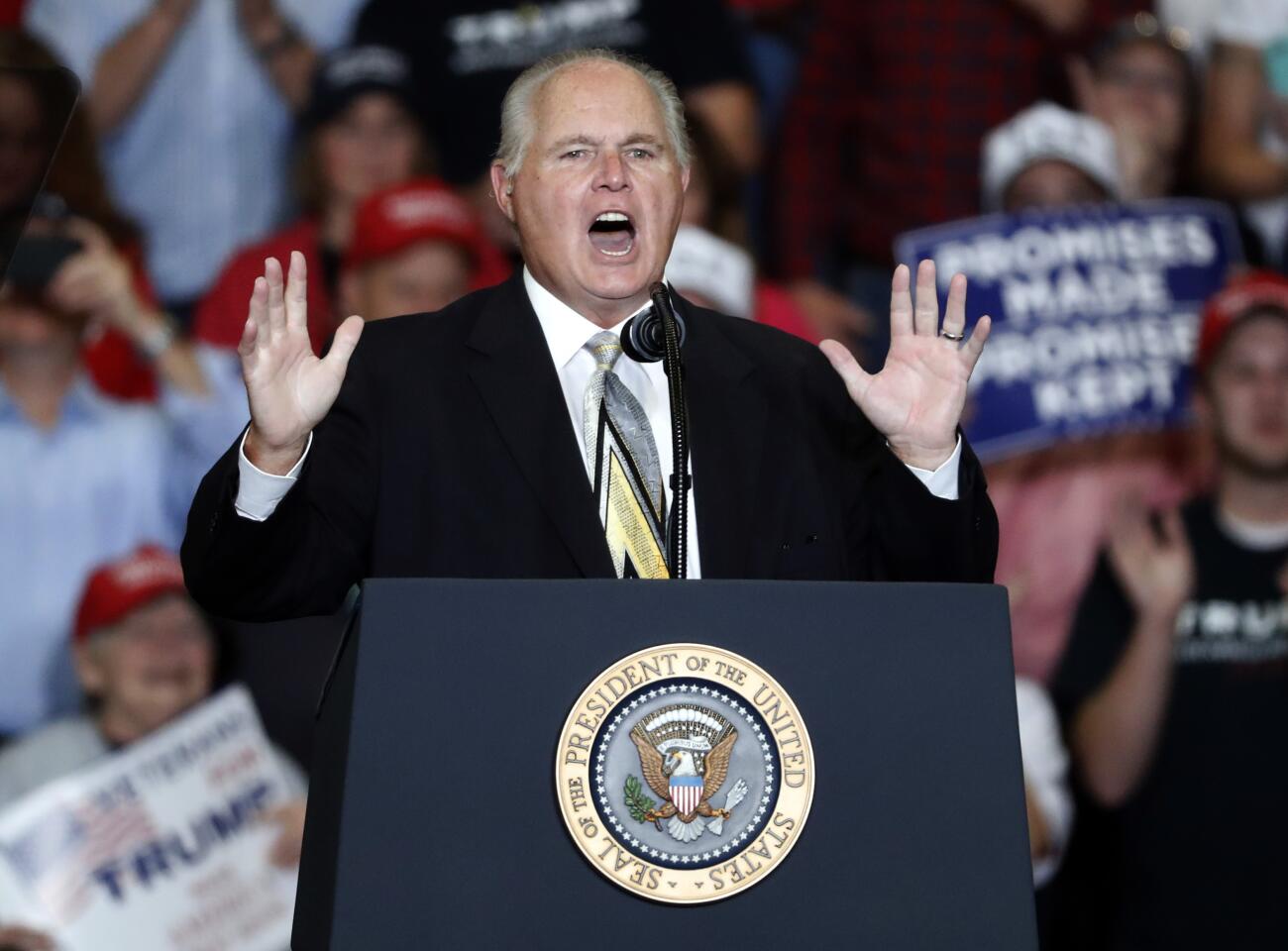 Rush Limbaugh gestures with both hands as he speaks from behind a podium.