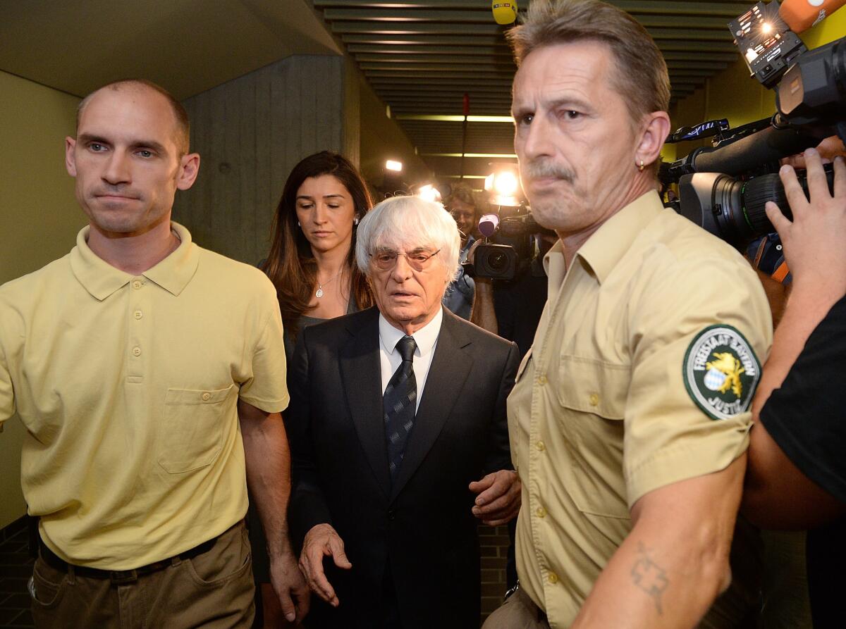 Formula One head Bernie Ecclestone, center, and his wife, Fabiana Flosi, depart the courthouse on Tuesday.