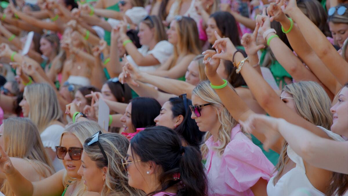 A large group of young women with arms raised during sorority recruitment.