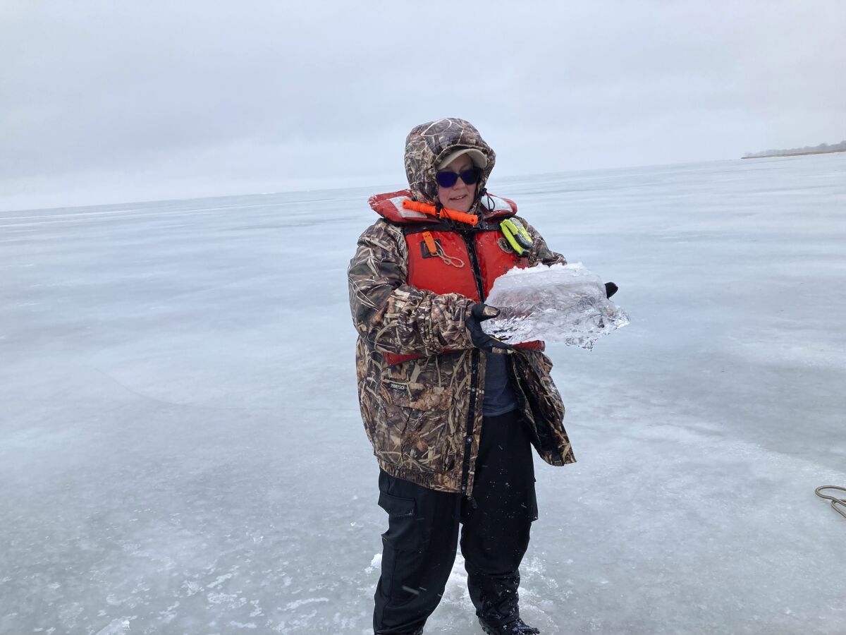 Bridget Wheelock, wetland ecology lab manager in Central Michigan University's biology department, holds a chunk of ice she extracted while conducting a field study on the frozen surface of Lake Huron's Saginaw Bay on Tuesday, Feb. 22, 2022 in Standish, Mich. (AP Photo/Mike Householder)
