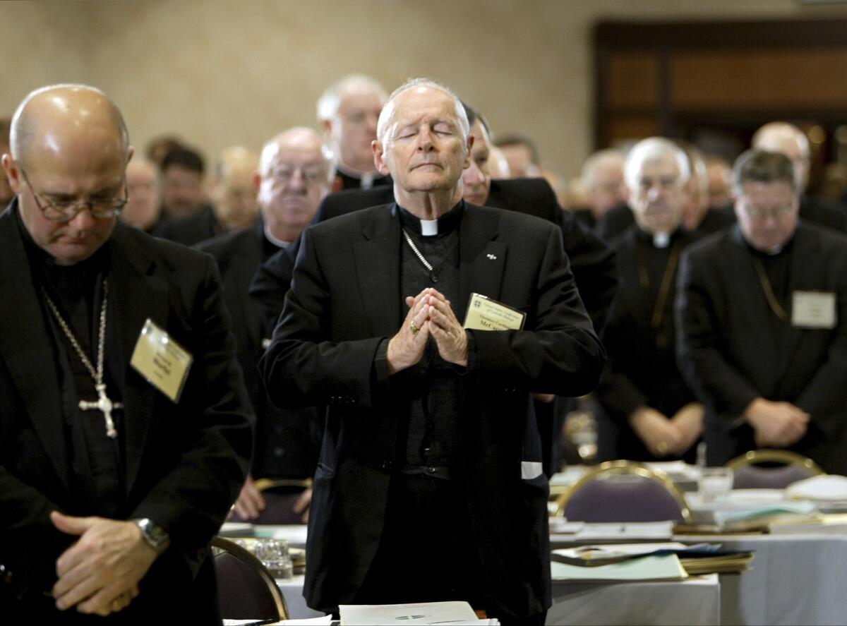 Then-Cardinal Theodore Edgar McCarrick, standing among other priests, closes his eyes and holds his hands in prayer.