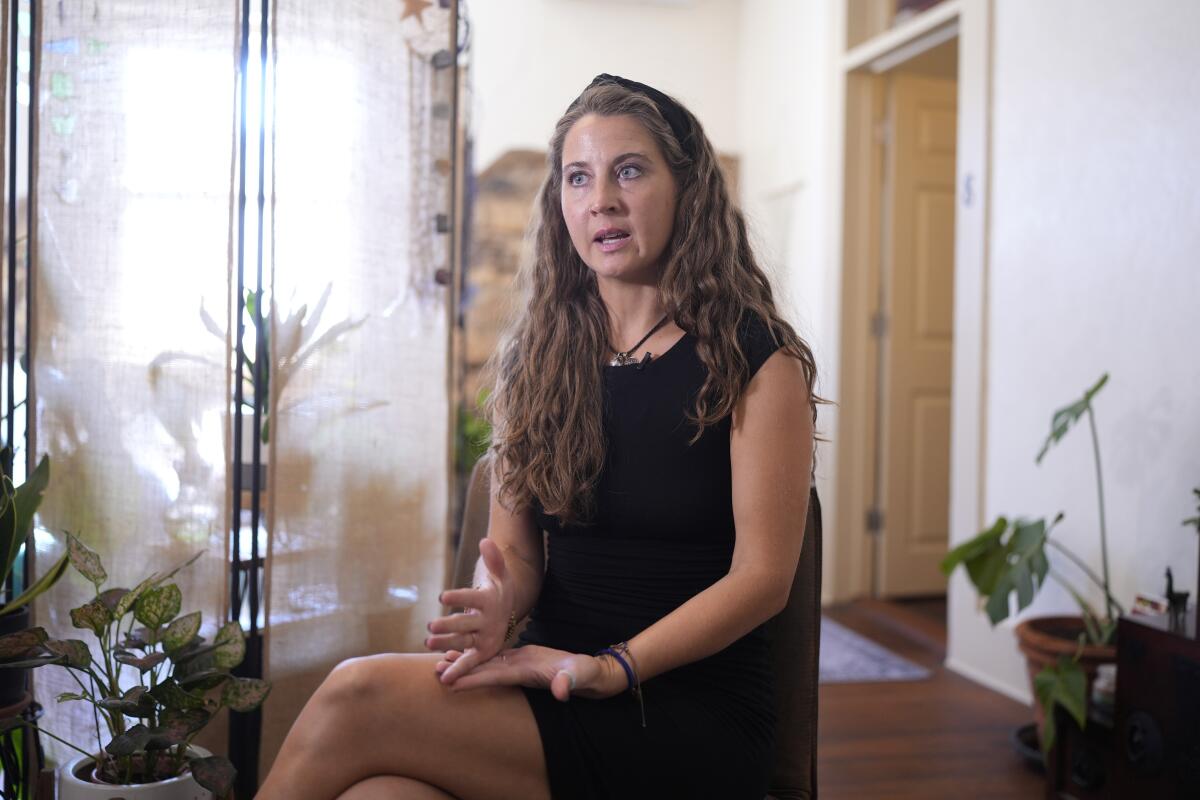 A woman sits and gestures as she speaks.