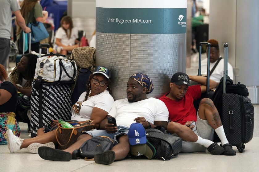 Alisson Bryan, Marcel Bryan and Terry Craig, wait to check-in their luggage for their flight home to Missouri at Miami International Airport, Saturday, July 2, 2022, in Miami. The group were on a cruise ship vacation in the Caribbean. The Fourth of July holiday weekend is jamming U.S. airports with the biggest crowds since the pandemic began in 2020. (AP Photo/Marta Lavandier)