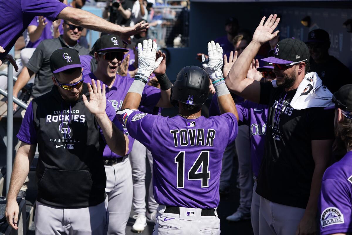 Colorado Rockies' Ezequiel Tovar (14) is high-fived in the dugout after his solo home run during the second inning of a baseball game against the Los Angeles Dodgers Wednesday, Oct. 5, 2022, in Los Angeles. (AP Photo/Marcio Jose Sanchez)