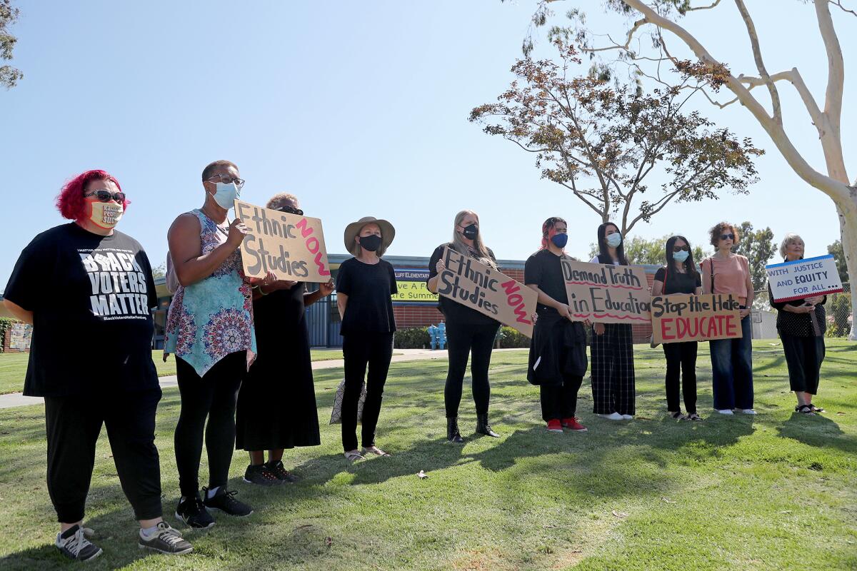 Members of Truth in Education hold up signs during a press conference at Eastbluff Elementary School.