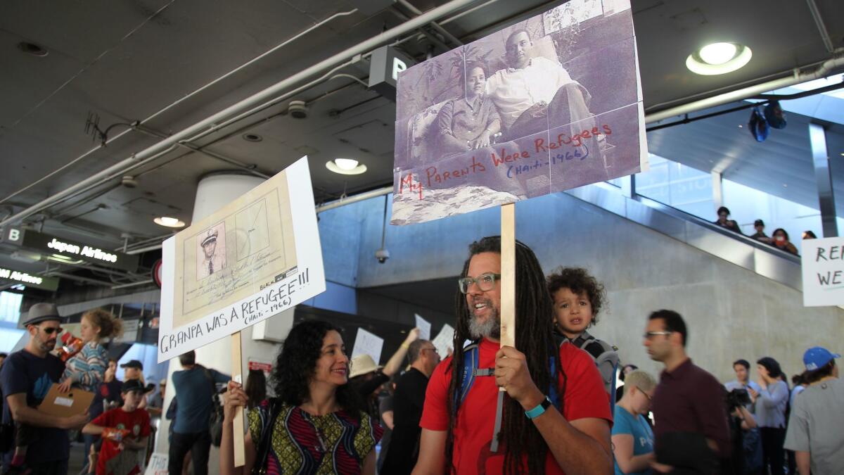 Painter Carolyn Castaño and writer Gary Dauphin protest at LAX with their son, Toussaint.