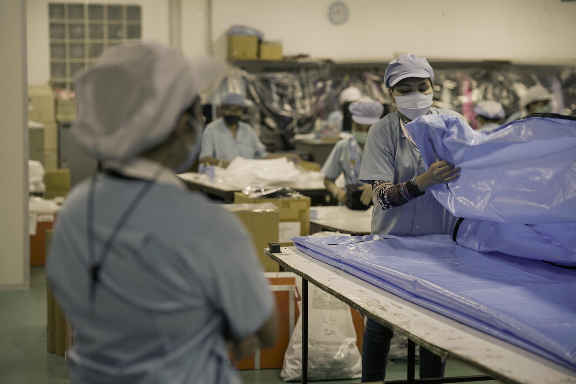 Workers inspect a body bag