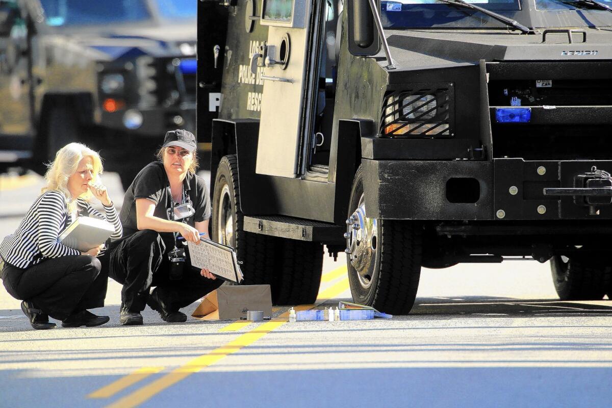 LAPD officers view the damage to the BearCat armored vehicle after a shootout with a gunman Aug. 18. The gunman was killed and an LAPD officer was wounded.