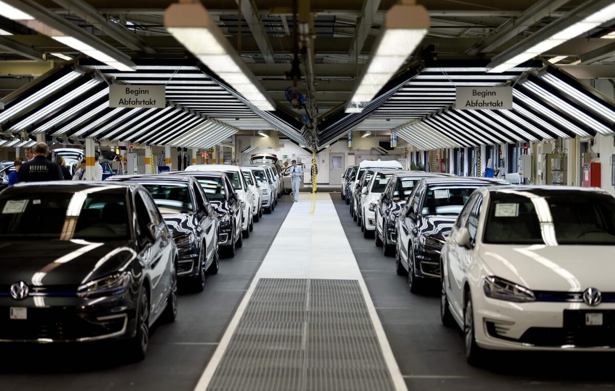 Volkswagen employees check cars on the assembly line of a plant in Wolfsburg, Germany, on Oct. 21, 2015.