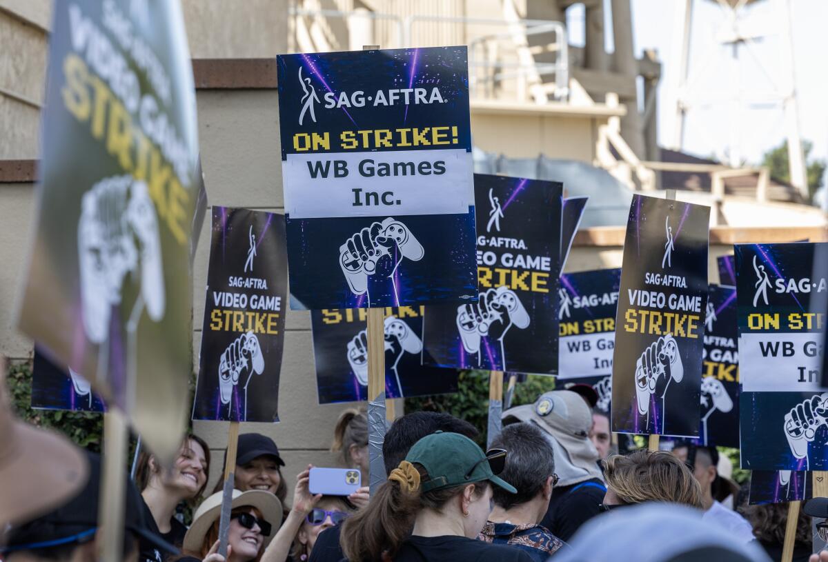 A crowd walking with picket signs that read "SAG-AFTRA on strike! WB Games Inc."