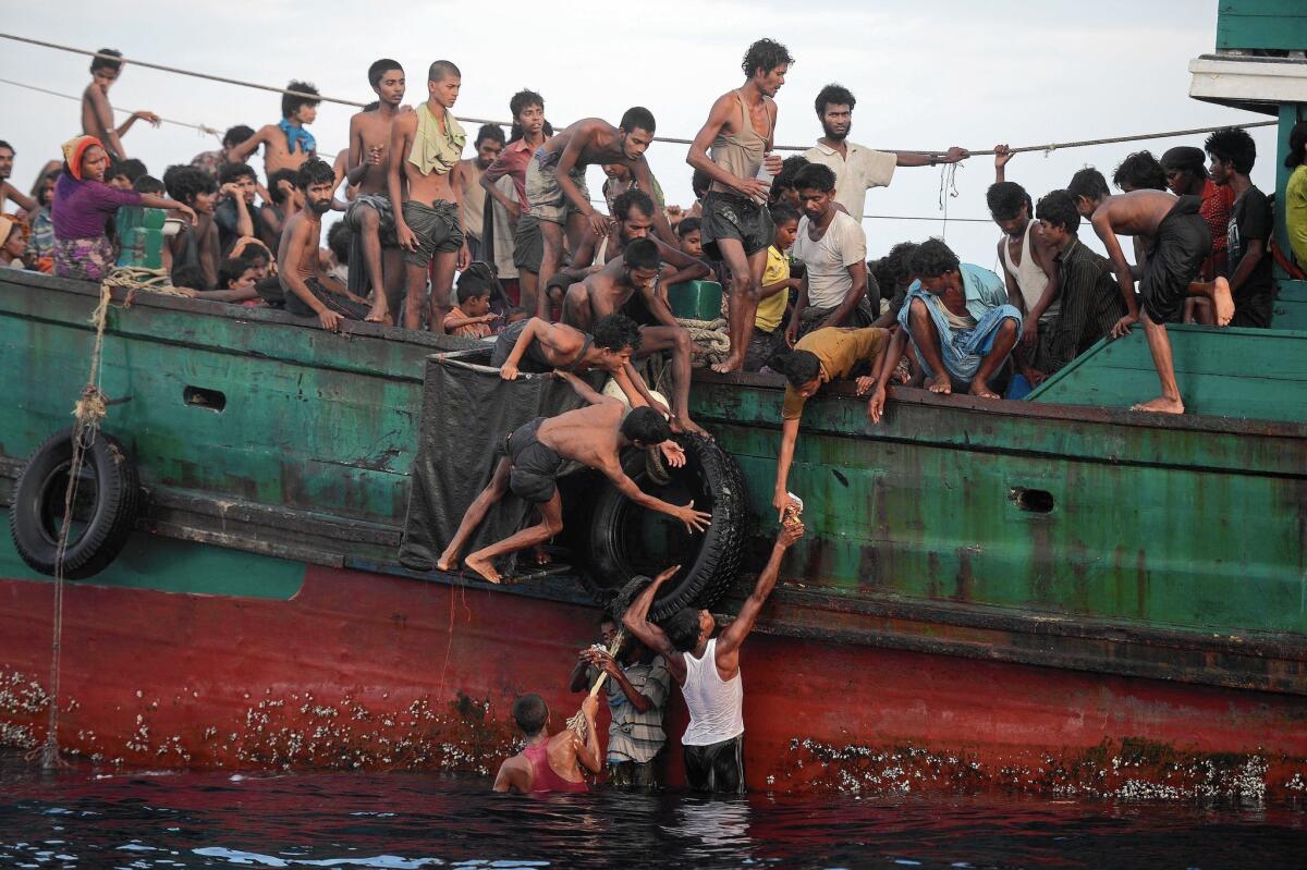 Rohingya migrants pass food supplies dropped by a Thai army helicopter to others aboard a boat drifting in Thai waters off the southern island of Koh Lipe on May 14.