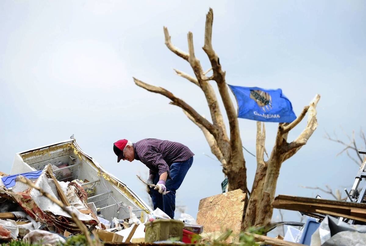 A tornado victim cleans debris from his home in Moore, Okla.