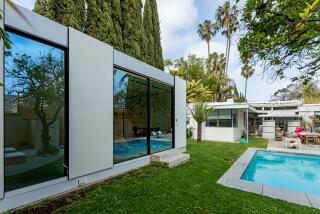 WEST HOLLYWOOD, CA - FRIDAY, MAY 19, 2023 - ADU, Lt, and the main house and pool. Modernist architect William Kesling designed this Streamline Moderne home for actor Wallace Beery in 1936. The home was in the news in 2017 when a developer purchased it and tried to tear it down. UCLA law professor Xiyin Tang and her husband Paul Laskow bought the home in 2020 after it was designated a historic landmark. Because of the designation, they can't update the exterior facade, so to accommodate their growing family, they added a prefab ADU by Cover in 2021. (Ricardo DeAratanha/Los Angeles Times)