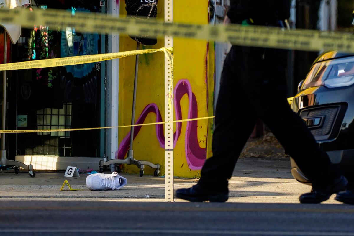 Law enforcement officers canvass the scene in front of a store front along Melrose Ave. following a fatal shooting