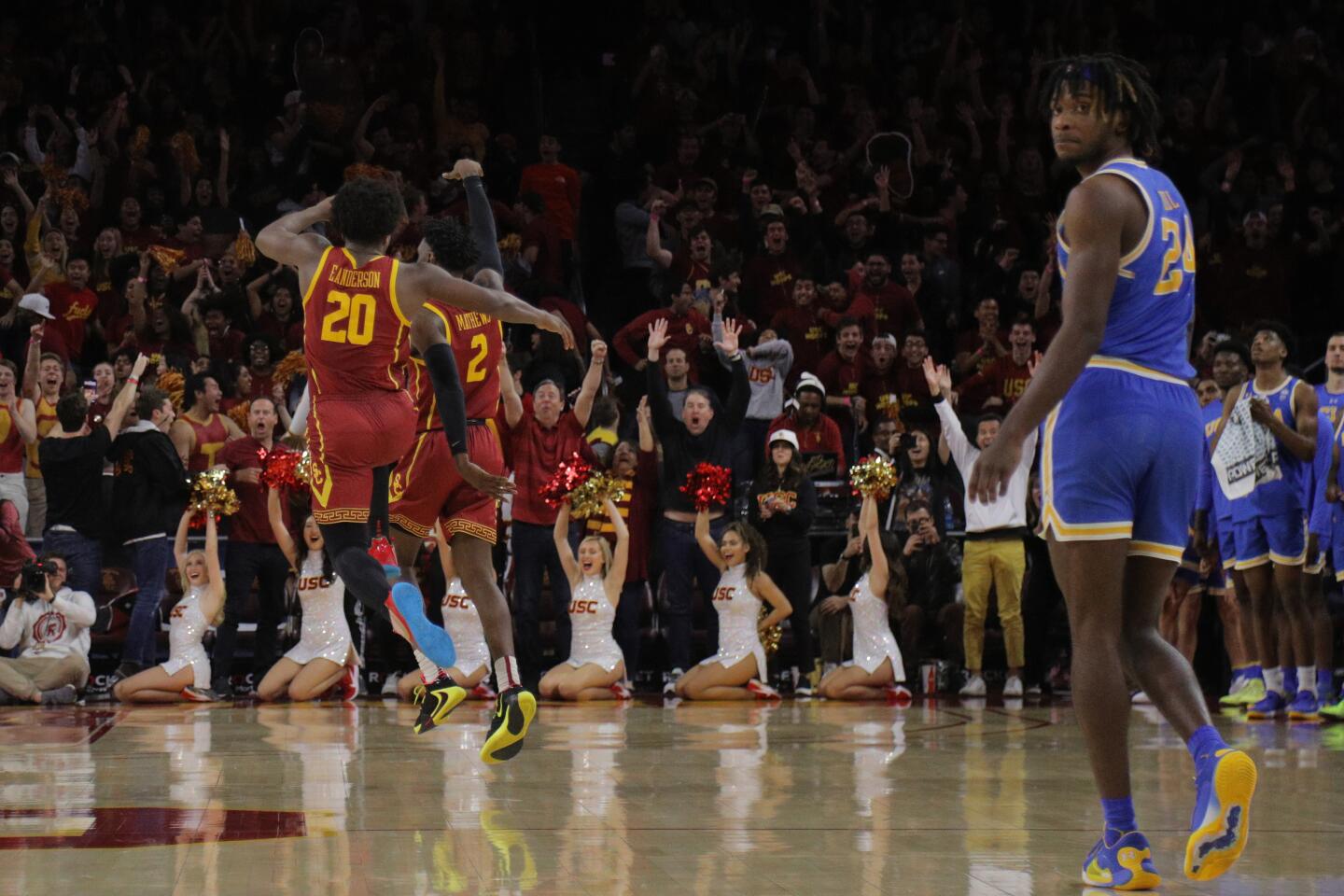 USC guard Jonah Mathews celebrates with teammate Ethan Anderson as UCLA's Jalen Hill looks at the scoreboard in the final moments of the Trojans' 54-52 victory at Galen Center on March 7, 2020.