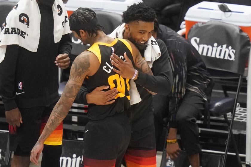 Utah Jazz's Donovan Mitchell, right, hugs Jordan Clarkson (00) after Clarkson came out of an NBA basketball game in the second half against the Orlando Magic, Saturday, April 3, 2021, in Salt Lake City. (AP Photo/Rick Bowmer)