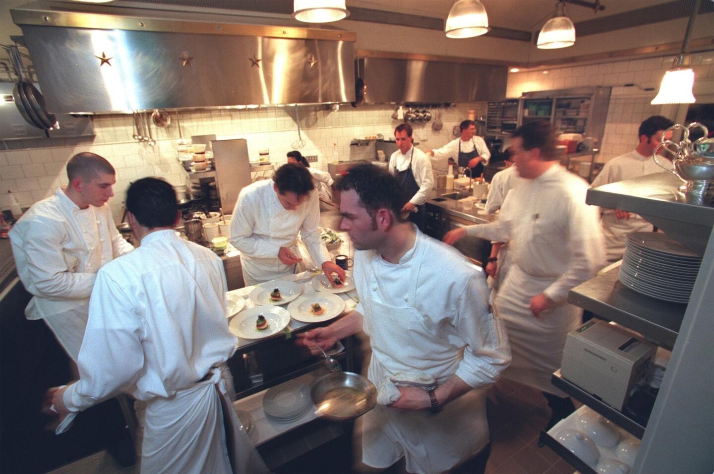 Waiters rush by Keller, third from left, as he puts the finishing touches on dishes for the dinner crowd in 1999.
