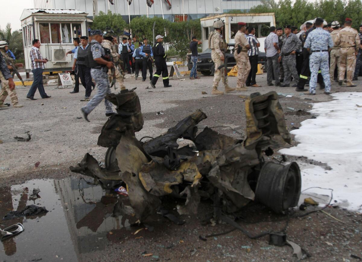 Residents and security forces inspect the scene of a car bomb attack in Basra, 340 miles southeast of Baghdad on Tuesday. Dozens of people were killed and wounded when insurgents unleashed a new wave of attacks across the country.