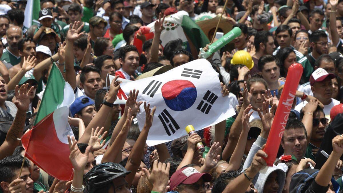 Fans hold a South Korea flag as thousands watch the World Cup game between Mexico and Sweden on a screen at the Angel of Independence monument in Mexico City.
