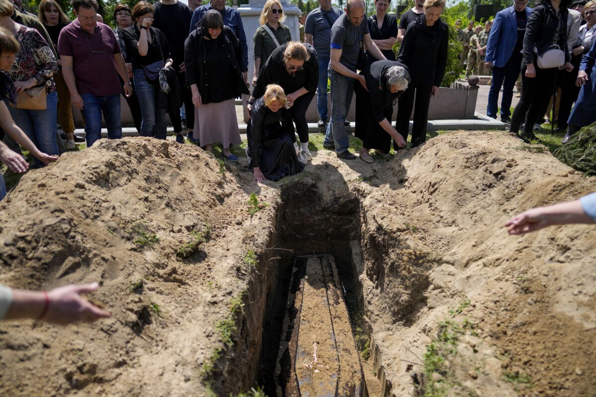 Relatives of Army Col. Oleksander Makhachek mourn during his funeral in Zhytomyr, Ukraine, Friday, June 3, 2022. According to combat comrades Makhachek was killed fighting Russian forces when a shell landed in his position on May 30. (AP Photo/Natacha Pisarenko)
