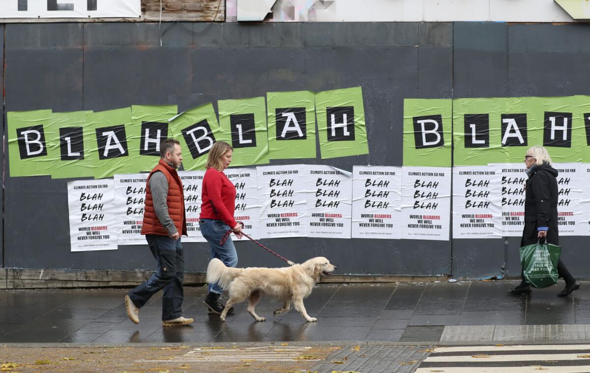 People walk past posters placed by environmental activists ahead of a protest march in Glasgow, Scotland.