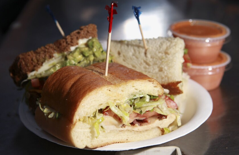 A chicken club with baguette, front, veggie supreme on squaw bread, and turkado on sour dough by Board and Brew during a media preview night at Petco Park. (Hayne Palmour IV/San Diego Union-Tribune, LLC)