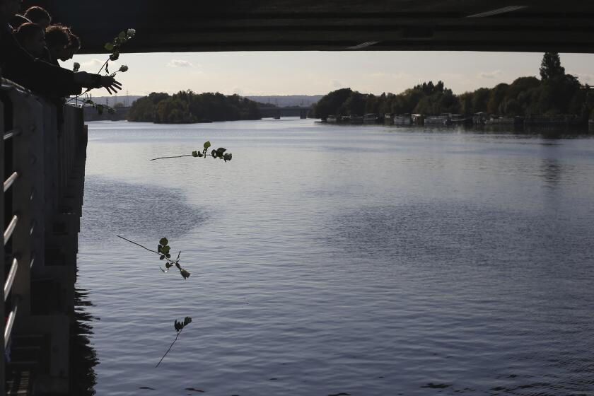 ARCHIVO - Invitados arrojan rosas al río Sena después de que el presidente francés Emmanuel Macron colocó una corona cerca del Pont de Bezons el sábado 16 de octubre de 2021 en Colombes, cerca de París. (AP Foto/Rafael Yaghobzadeh, Pool, Archivo)